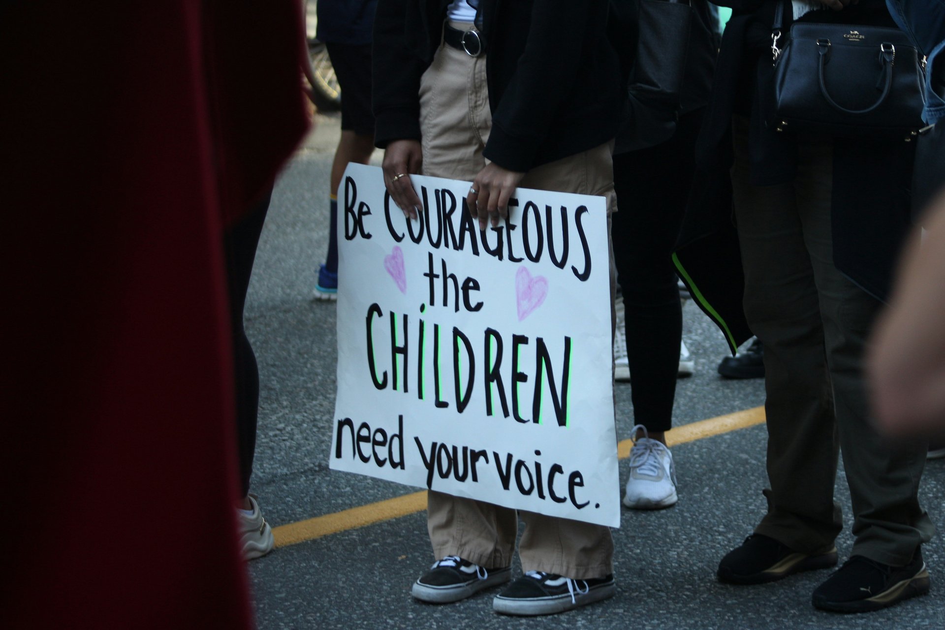 Person holding a sign about children needing a voice